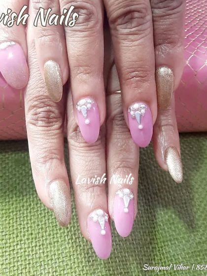 A sophisticated design with pink and gold glitter nails, featuring accent nails with intricate pearl and rhinestone embellishments.