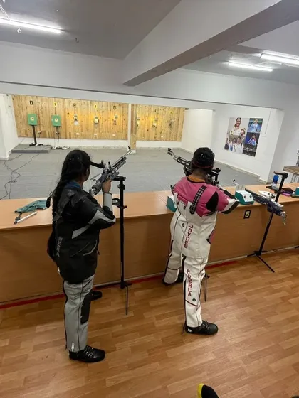 Two of our rifle shooters practicing side by side in our indoor range. This setup mimics a competitive environment, helping them get used to shooting alongside others.
