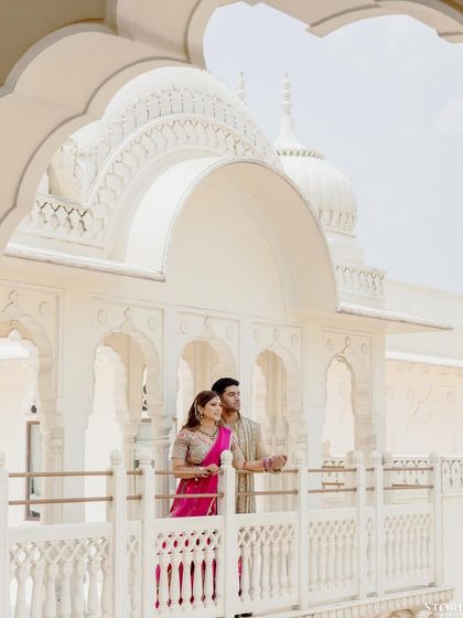 A beautiful portrait of the couple on a white marble balcony, the architecture perfectly framing their elegant pose.