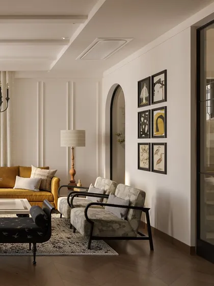 A gallery wall of curated art adds a personal touch to this elegant living area. The arrangement complements the room's classic paneling and arched doorways, showing how we integrate personal stories into a home's design.