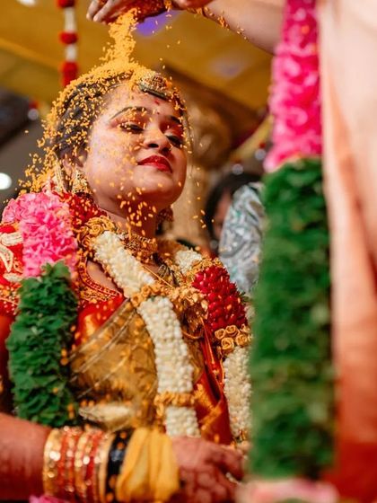 A bride being showered with turmeric and rice during a wedding ritual. We capture the color, tradition, and emotion of the moment.