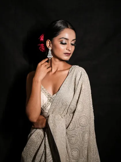 Elegance personified. A close-up studio portrait for Diwali, focusing on the model's serene expression, intricate hairstyle with a red rose, and beautiful saree.