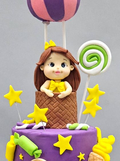 A close-up of the princess figurine in a hot air balloon, ready to float above the Candyland-themed anti-gravity cake.