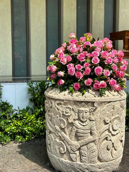 Our hand-carved 'Tara' planter looks absolutely dreamy in this client's home. The intricate details of the stone carving are softened by the abundance of delicate pink roses, creating a truly romantic display.