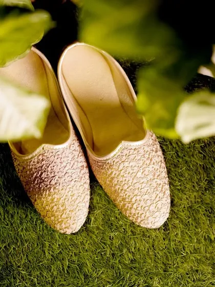 A detail shot of the groom's traditional 'juttis' resting on the grass.
