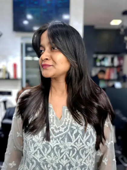 A happy client showing off her new look. This shoulder-length cut with face-framing layers and a smooth finish is a classic and timeless style.