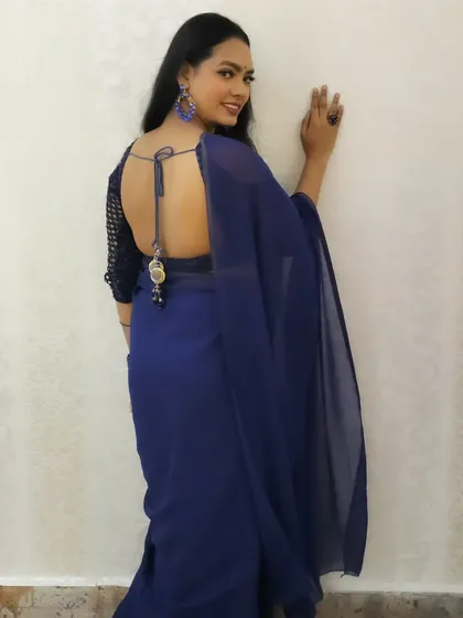 A stunning backless blouse design paired with a simple blue saree, perfect for a modern party look.