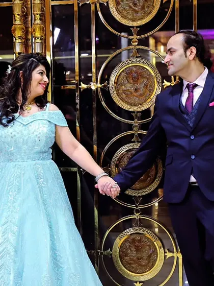A full-length shot of a couple holding hands in front of an elegant, decorative gate, ideal for an engagement or anniversary album.