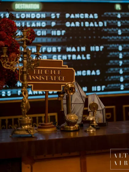 Details matter in storytelling. The reception desk featured vintage props like an old-fashioned telephone, candelabra, and signage, all set against the backdrop of the departures board to complete the immersive train station feel.