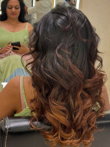 A back view of a client's hair in the salon chair, showing off her new ombré color. The mirror reflection captures the moment of transformation.