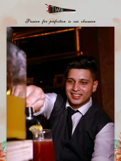 A smiling bartender prepares a drink, showcasing the friendly and approachable service our team provides.