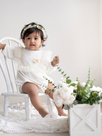 A beautiful sitter session portrait with a simple floral theme. The white chair and flowers create a fresh, clean look.