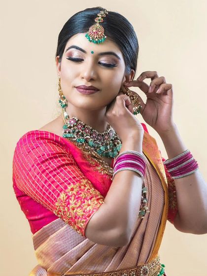 A candid shot of the model adjusting her earring, showing the beautiful details of the jewellery.