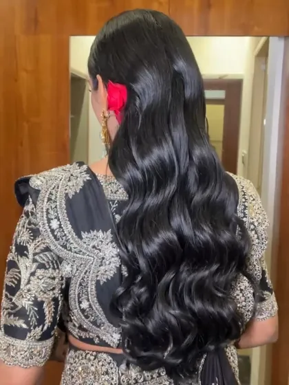 A glamorous open hairstyle with old Hollywood waves and a red floral accessory.