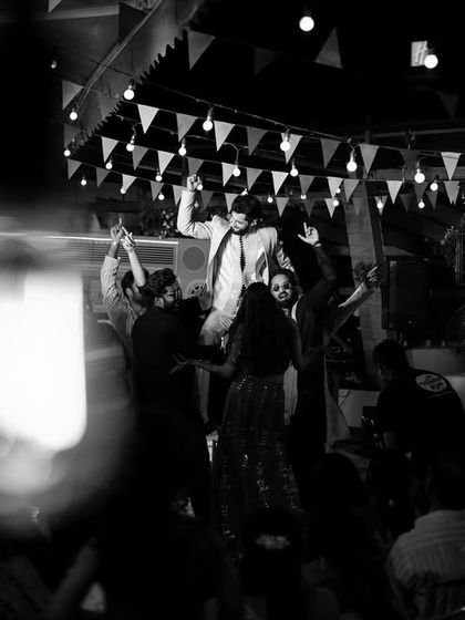 A wide-angle black and white shot capturing the energy of the groom's dance party.