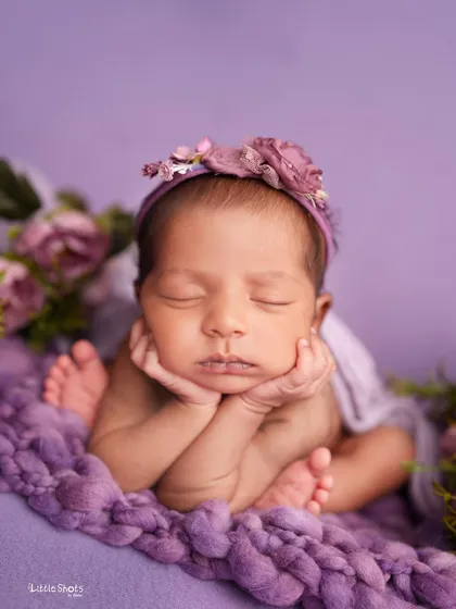 Dreaming in lavender. This sweet 'chin on hands' pose is enhanced by the soft purple tones of the blanket and floral headband.