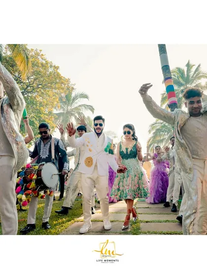 The couple enters their wedding carnival with dhol players and dancers, creating an energetic and celebratory procession.