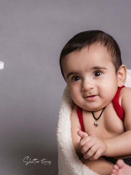 A six-month milestone session featuring a chubby, happy baby in cute red suspenders.