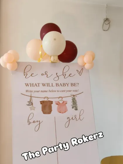A "He or She" gender reveal voting board, allowing guests to guess the baby's gender and write their names.