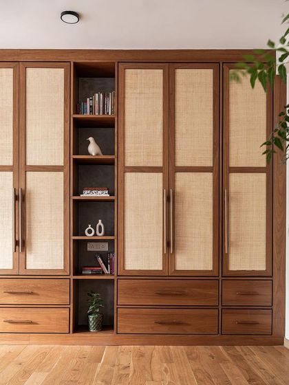 This master bedroom wardrobe spans the entire wall, finished in veneer and rattan to create a warm, earthy vibe. To break the monotony, I added open shelves with a concrete-textured background for visual interest.