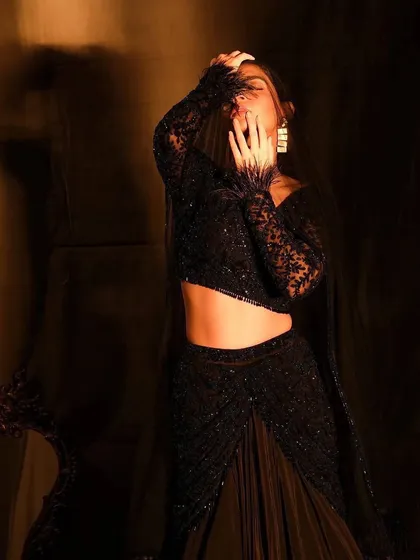 An expressive shot of a model in a dramatic black ensemble. The makeup is dark and moody, with a focus on the eyes, creating a look of intense glamour perfect for a cocktail evening.