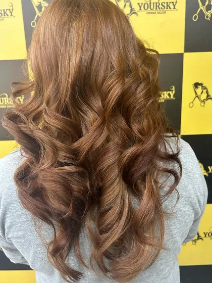This client's global hair color in a warm copper tone looks fantastic styled with bouncy curls.
