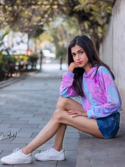 A full-body seated portrait that showcases a casual, cotton-candy-colored look. This shot captures a quiet, thoughtful moment amidst the urban landscape, perfect for a lifestyle portfolio.