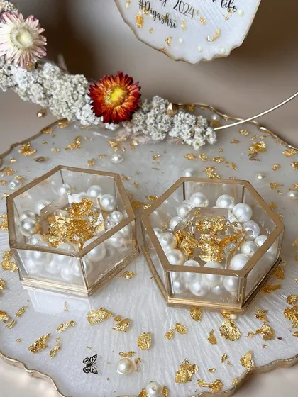 A detailed shot of the pearl and gold flake-filled ring boxes on the white platter.