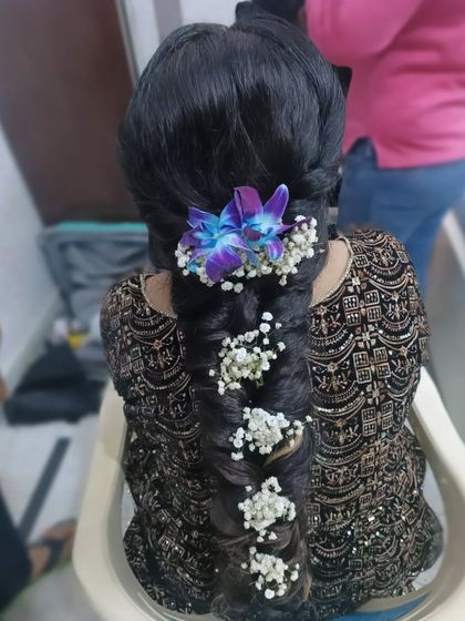 A stunning, thick braid adorned with fresh baby's breath and a vibrant purple orchid. This is a beautiful choice for a Mehendi or Haldi ceremony.