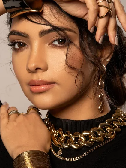 A close-up beauty shot where chunky gold accessories take center stage. The styling is modern and edgy, showing how to layer different pieces for a bold, fashion-forward look.