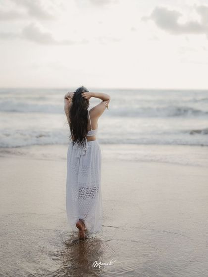 A beautiful solo portrait of the bride-to-be, looking out at the ocean, her hair blowing in the sea breeze.