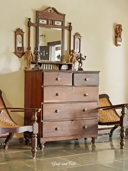 A collection of antique furniture, including a chest of drawers with a matching mirror and classic planter's chairs. This vignette at Villa Magnolia is a nod to the colonial history and heritage of Coorg.