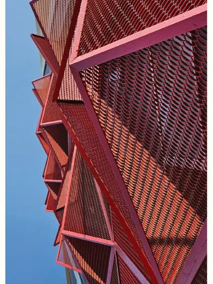 A close-up detail of the red metal mesh, showing the texture and play of light.