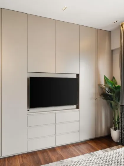 This image shows the complete integrated wall unit, combining a full-height wardrobe with a TV console and drawers. The neutral color and clean lines help the large storage unit blend into the wall, making the room feel spacious and organized.