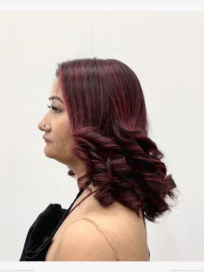 A client with a fresh red-toned hair color, styled into tight, defined curls. This look shows how color can enhance texture and create a completely new personality for your hair.