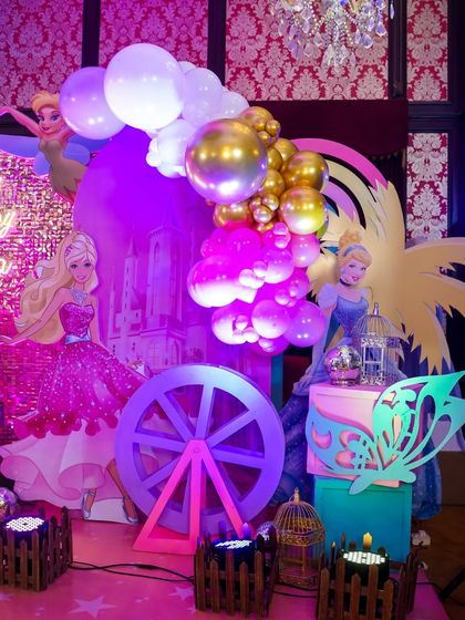 A closer look at the Barbie stage decor, with character cutouts, a decorative wheel, and butterfly accents.