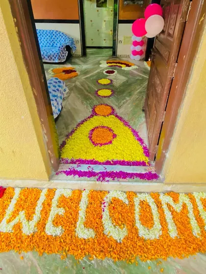 A 'WELCOME' message created with marigold flowers at the doorstep for a baby's homecoming.