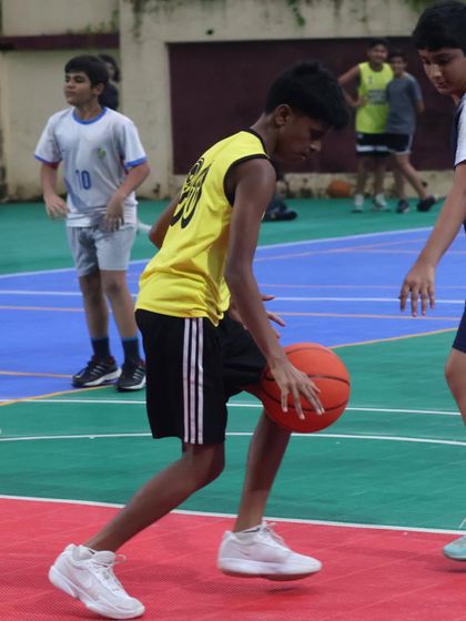 A young athlete practices his dribbling technique, keeping his eyes up to read the court. This is a key skill we teach for better game awareness.