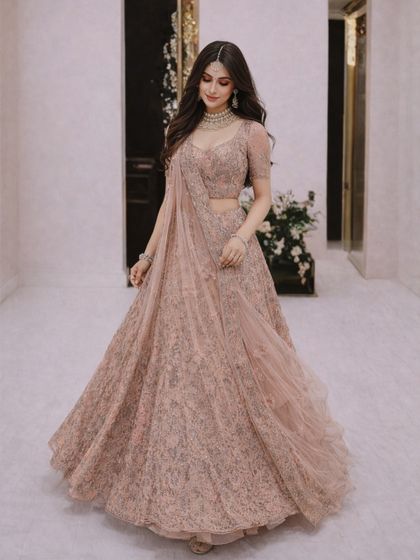 The flowing skirt of this dusty pink lehenga creates a beautiful sense of movement. The delicate, all-over embroidery gives it an ethereal and romantic quality.