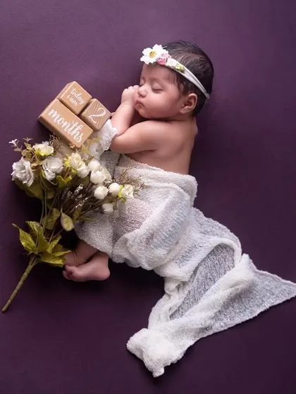 Another two-month milestone portrait. The baby is gently wrapped and posed with flowers, creating a delicate and artistic image to mark their second month.
