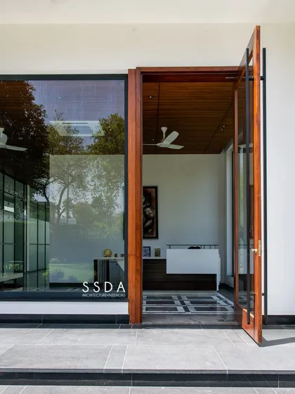 The entrance to 'The Green Axis' office, where a large wooden door opens into a space defined by its connection to the courtyard. The design blurs the line between the built environment and nature.