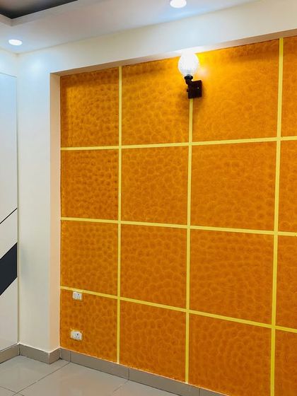 A bedroom design combining a bold, textured orange wall with a custom wardrobe featuring a black and white chevron pattern.