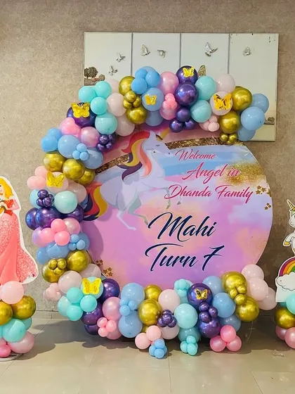 A magical unicorn and princess theme for Mahi's 7th birthday. This setup features a custom circular backdrop, character cutouts of princesses and unicorns, and a pastel and gold balloon arch.