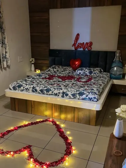 A simple and sweet romantic setup with a rose petal heart on the floor, a "love" balloon, and a champagne bottle foil.
