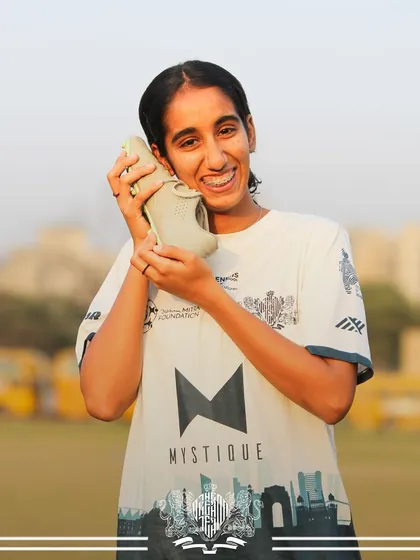 A lighthearted moment. A player playfully holds a shoe to her ear, showing the fun side of team life.