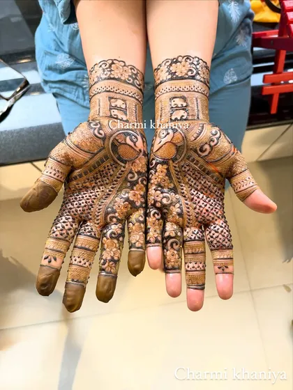 A lovely mehendi design featuring a prominent peacock on the palm. The wrist cuff has a 'jharokha' or window design, adding a touch of architectural beauty.