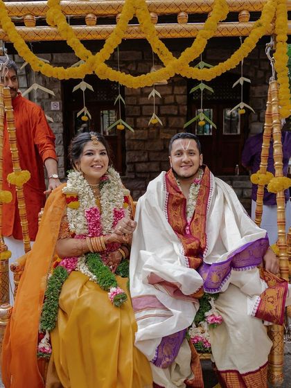 A couple enjoys a ride on a swing decorated with bright marigolds, a classic element of many Indian pre-wedding ceremonies like the haldi.