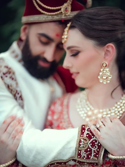 An intimate close-up of a multicultural couple, focusing on the bride's beautiful jewelry and the tender connection between them.