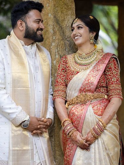 A classic portrait of a couple standing by ancient stone pillars, their smiles reflecting their love.