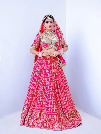 A full-length bridal portrait against a clean white studio background. This style puts all the focus on the stunning pink lehenga and the bride's complete look.